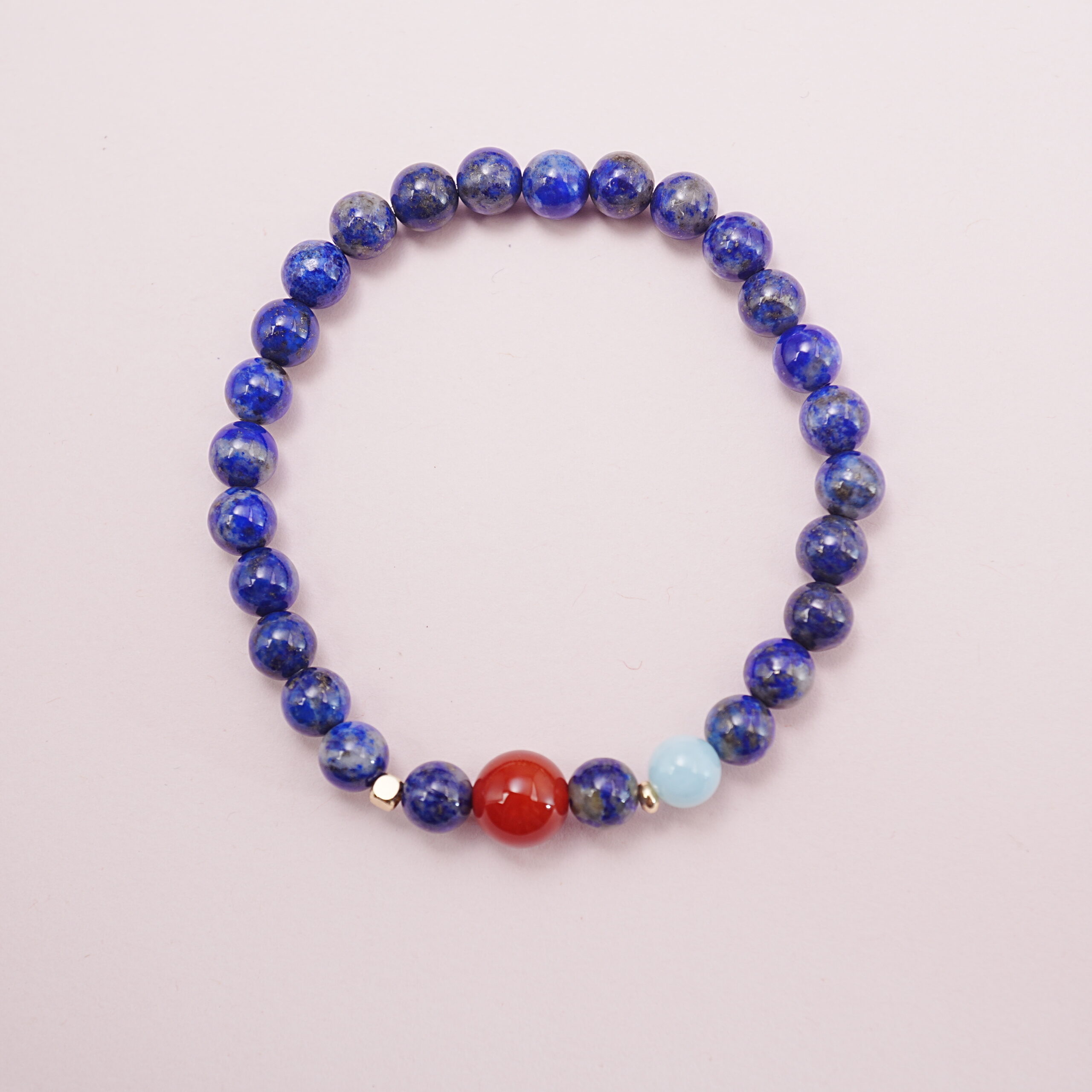 lapis-lazuli-carnelian-aquamarine-bracelet-main.jpg Lapis lazuli bracelet with a carnelian accent bead and aquamarine charm displayed on a soft background.