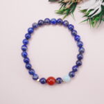 Lapis lazuli bracelet with carnelian and aquamarine accents styled beside greenery decoration.