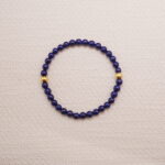 Lapis lazuli bracelet with small gold accents displayed on a soft textured background.