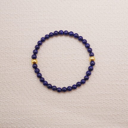 Lapis lazuli bracelet with small gold accents displayed on a soft textured background.