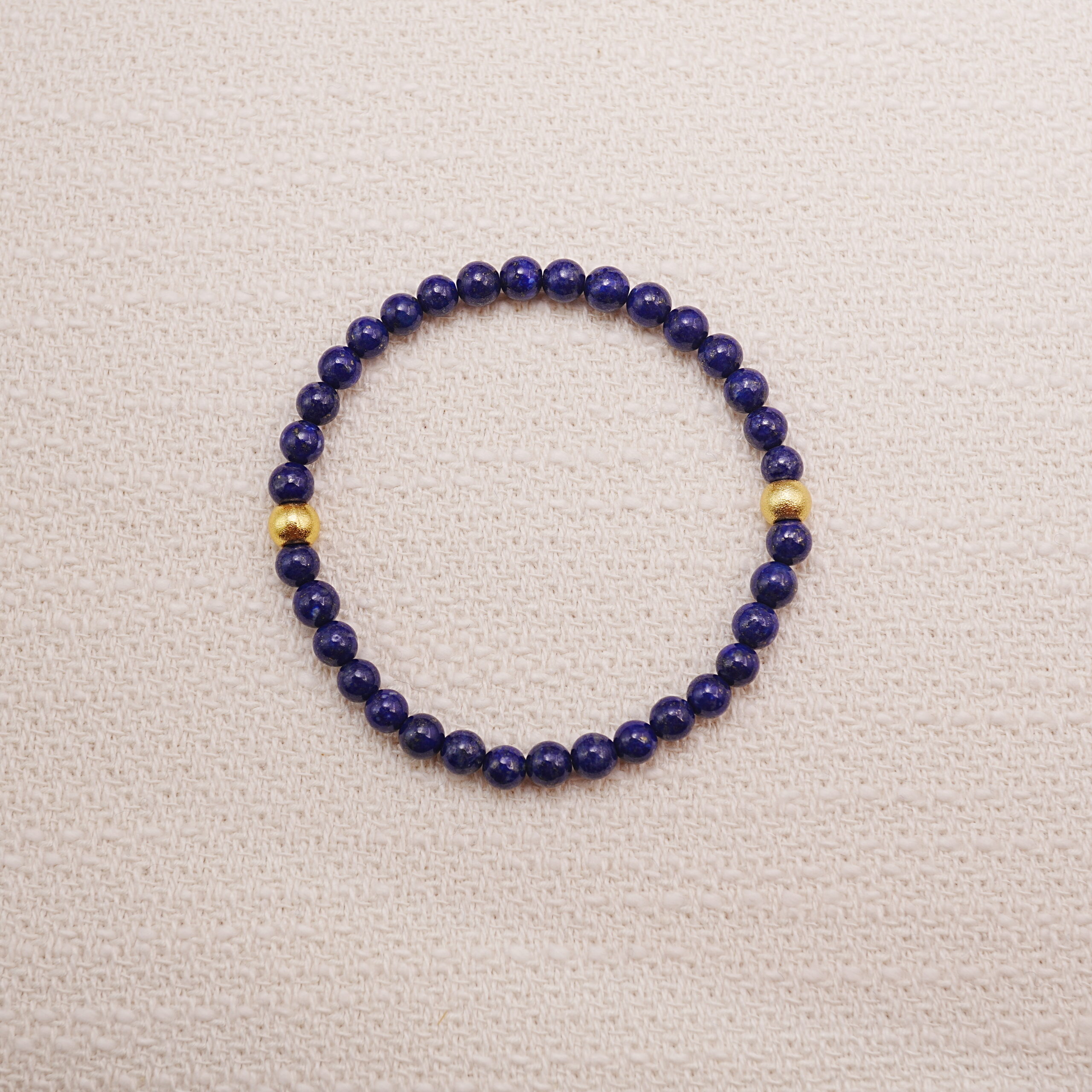 lapis-lazuli-gold-accent-bracelet-main.jpg Lapis lazuli bracelet with small gold accents displayed on a soft textured background.