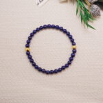 Lapis lazuli bracelet with gold accents placed beside decorative plants for a cozy scene.