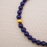 Close-up view of the lapis lazuli bracelet highlighting the smooth blue beads and gold accent bead.