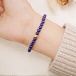 Lapis lazuli bracelet with gold accents worn on the wrist, showing a simple and elegant style.