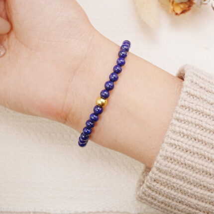 Lapis lazuli bracelet with gold accents worn on the wrist, showing a simple and elegant style.