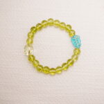 Peridot beaded bracelet with an accent carved bead displayed on a soft surface.