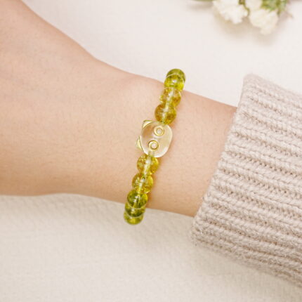 Peridot bracelet worn on the wrist, showing the carved accent bead.