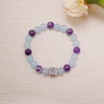 Aquamarine and amethyst bracelet with silver rose charm styled next to soft florals.