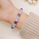 Close-up of aquamarine and amethyst bead bracelet worn on wrist.