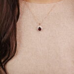Woman wearing a rose gold ruby halo pendant necklace for an elegant and classic look.