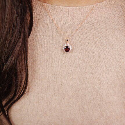 Woman wearing a rose gold ruby halo pendant necklace for an elegant and classic look.