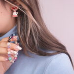 Model showcasing a colorful gemstone bracelet and Santa Claus earrings with red ribbons