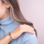 A model wearing the green chalcedony bracelet with a carnelian accent and the matching earrings, creating a perfect balance of elegance and style.