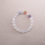 White Moonstone beaded bracelet with pastel accent gemstones on a soft beige background.