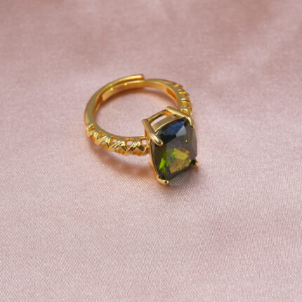 Peridot statement ring with gold-toned band displayed on pink satin.