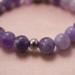 Close-up of amethyst beads with silver accent, highlighting natural crystal texture and polished shine.