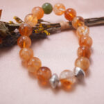Lifestyle photo of citrine bracelet with silver spiral beads placed on soft pink fabric.