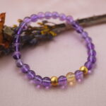 Lifestyle photo of amethyst and citrine bracelet placed on soft fabric with warm lighting.