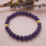 Lifestyle shot of deep amethyst bracelet on soft fabric, glowing with a peaceful purple hue.