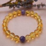 Lifestyle photo of citrine and amethyst bracelet on soft fabric, glowing with light energy.