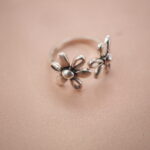 Double daisy adjustable silver ring featuring two blooming floral designs, symbolizing joy and renewal.
