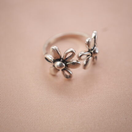 Double daisy adjustable silver ring featuring two blooming floral designs, symbolizing joy and renewal.