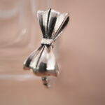 Lifestyle shot of bow silver ring on a soft pink background, radiating sweet vintage vibes.