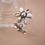 Lifestyle image of double daisy silver ring placed on a soft pink background, exuding romantic spring vibes.