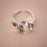 Close-up of silver open ring showing petal-shaped ends and smooth polished texture.