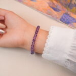 Back view of amethyst bracelet highlighting its smooth round beads and golden accents.