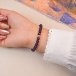 Back view of the deep amethyst bracelet, highlighting smooth round crystals and golden bead details.