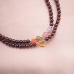 Close-up view of the garnet beads and the central amethyst and colored gemstone accents of the necklace.