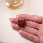 Red jasper crystal cube in hand, rich in earthy red tones for strength and grounding.