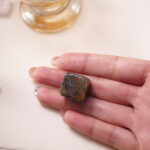 Labradorite crystal cube in hand, shimmering with blue iridescence to enhance intuition and spiritual protection.