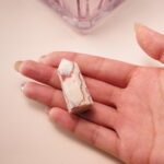 Red line jasper crystal point in hand, displaying earthy red and beige tones for grounding and stability.