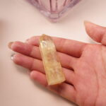 Citrine crystal point in hand, glowing with golden light that attracts wealth and positivity.