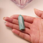 Amazonite crystal point in hand, showing serene turquoise tones for courage and emotional balance.