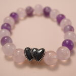 Close-up detail of amethyst and rose quartz bracelet featuring a silver double-heart bead, showing the smooth polish, natural color gradient, and romantic design.1