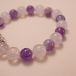 Close-up detail of amethyst and rose quartz bracelet featuring a silver double-heart bead, showing the smooth polish, natural color gradient, and romantic design.2