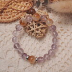 Amethyst and citrine bracelet displayed in a lifestyle setting under daylight, showcasing its soothing and radiant energy with harmonious purple and yellow hues.