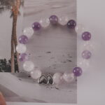 Amethyst and rose quartz bracelet with a silver double-heart accent displayed in a natural lifestyle setting under daylight, capturing its soothing pastel tones and loving energy.