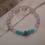 Kunzite, amazonite, and clear quartz bracelet with a silver heart accent displayed in a natural lifestyle setting under daylight, highlighting its serene pastel hues and calming energy.