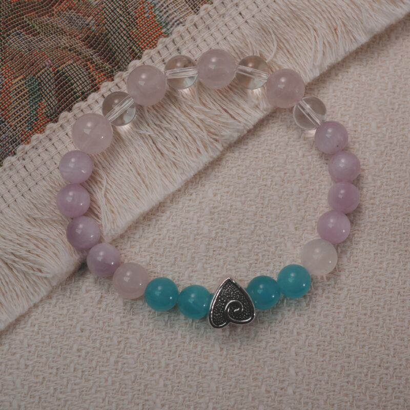 Kunzite, amazonite, and clear quartz bracelet with a silver heart accent displayed in a natural lifestyle setting under daylight, highlighting its serene pastel hues and calming energy.