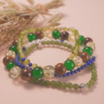Green and gold good luck bracelet stack displayed in soft natural light, radiating harmony and positive energy.