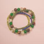 Good luck intention bracelet stack with green and golden gemstones, symbolizing growth, positivity, and fortune.